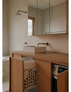 a washer and dryer in a bathroom with a mirror over the sink above it