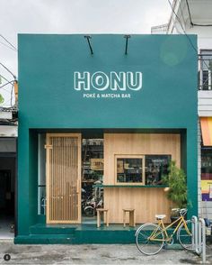 a bike parked in front of a green building with the word honu written on it