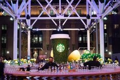 a table topped with lots of bottles and cups filled with liquid next to a giant plant