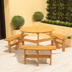 a wooden table and benches on a patio with potted plants in the background,