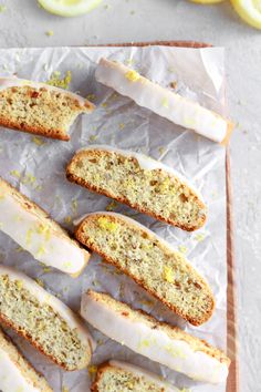 slices of lemon bread sitting on top of a piece of wax paper next to sliced lemons