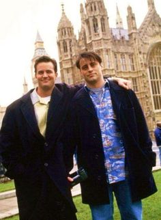 two men standing next to each other in front of big ben and the houses of parliament