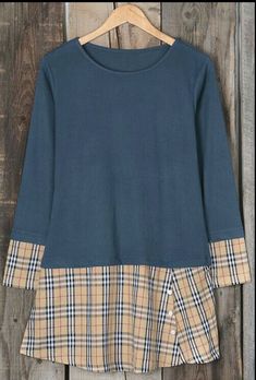 a blue shirt hanging on a wooden wall next to a hanger with a checkered skirt