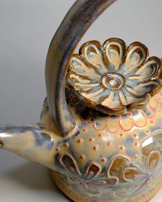 a ceramic teapot with a flower decoration on it