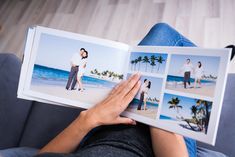 a person sitting on a couch holding an open book with pictures of people in them