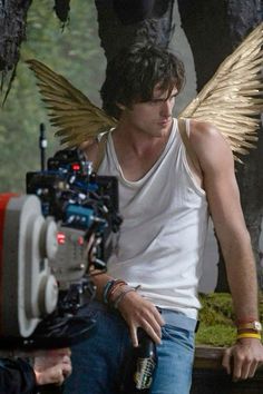 a man sitting next to a camera with angel wings on his chest and arm around him