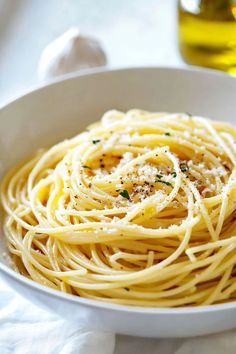 a white bowl filled with pasta and parmesan cheese on top of a table