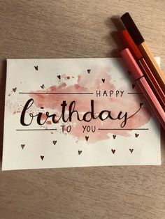 a piece of paper with the words happy birthday to you written on it next to two crayons