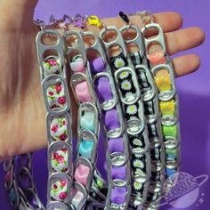 a hand holding four bracelets with flowers and hearts on them, all in different colors