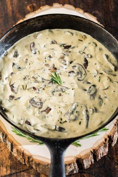 a skillet filled with mushroom sauce on top of a wooden table