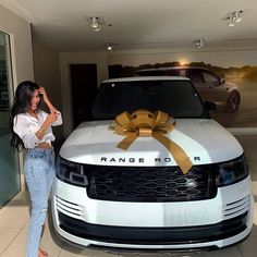 a woman standing next to a range rover with a bow on it