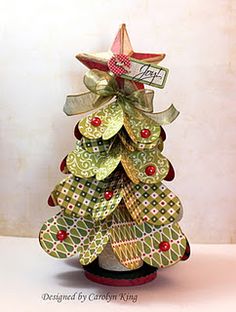 a small christmas tree made out of paper with ribbons on it's sides and a tag hanging from the top