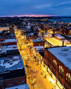 an aerial view of a city at night with snow on the ground and buildings lit up