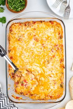 a casserole dish with meat and cheese in it on a table next to bread