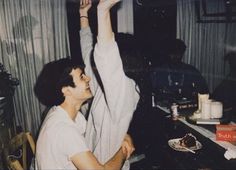 a man is holding up his arms in the air while sitting at a table with other people