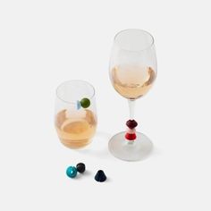 two wine glasses sitting next to each other on a white surface with beads in them