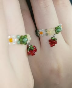 two hands with rings made out of beads and fruit on the ring fingernails