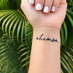 a woman's wrist tattoo with the word ahana on it, and an image of a palm tree in the background