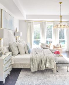 a bedroom with a large bed and chandelier hanging from the ceiling