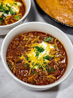 two bowls of chili with cheese and sour cream