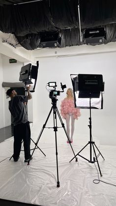 a woman in a pink dress is sitting on a white sheet while another man stands behind her