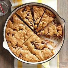 a pan filled with chocolate chip cookies on top of a table next to two glasses