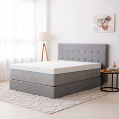 an image of a mattress in the middle of a room with a side table and lamp