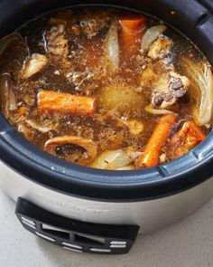 a crock pot filled with stew and carrots on top of a white counter