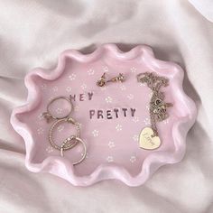 a pink tray with two key chains and a heart charm on it that says, hey pretty