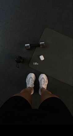 someone is standing on the floor with their feet up next to a gym mat and dumbbells