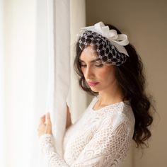 a woman wearing a veil and holding on to the side of a window sill