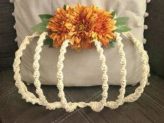 a crocheted pumpkin pillow with a flower on it's head sitting on a couch