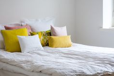 a white bed topped with lots of pillows