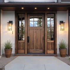 the front door of a house with two planters on either side and one light on