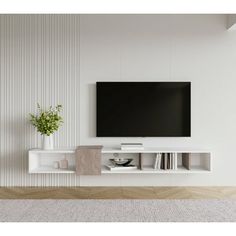 a flat screen tv mounted to the side of a white wall next to a potted plant