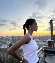 a woman standing on top of a roof with her hands on her hips and looking off into the distance