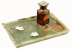 a bottle of perfume sitting on top of a glass tray with flowers in the water