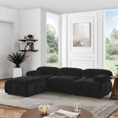 a living room with a large black couch and coffee table in front of a window