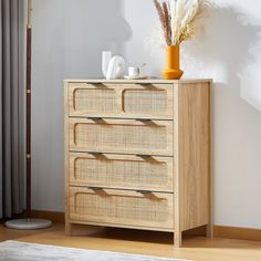 a wooden dresser with three drawers next to a vase and lamp on top of it