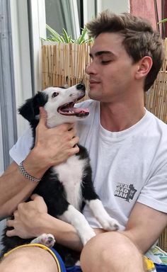 a man holding a black and white dog in his lap