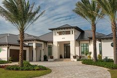 a white house with palm trees in front of it and a driveway leading to the front door