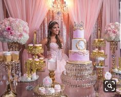 a woman standing in front of a cake surrounded by pink and gold decorations on top of a table