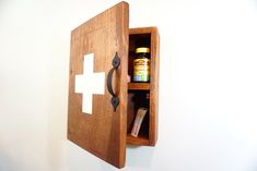 the medicine cabinet is made out of wood and has an iron cross on it's door