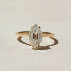 an engagement ring with a pear shaped diamond in the center, on a white surface