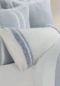 a close up of a bed with blue and white sheets, pillows and pillow cases