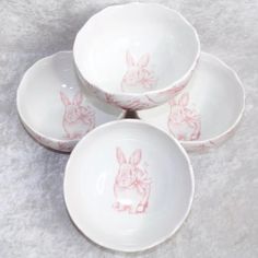 three white bowls with pink rabbit designs on them