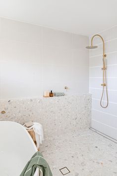 a bathroom with a tub, shower head and white tile walls on the wall next to it