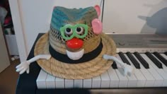 a toy clown hat sitting on top of a piano with green goggles and a red nose