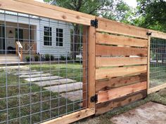 a wooden fence with metal bars on the top and bottom, in front of a house