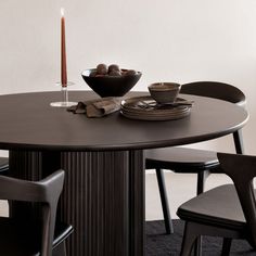 a dining table with two chairs and a bowl of fruit on the plate next to it